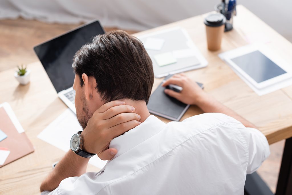 vistacreate 416989778 stock photo back view office worker aching neck sitting workplace blurred background