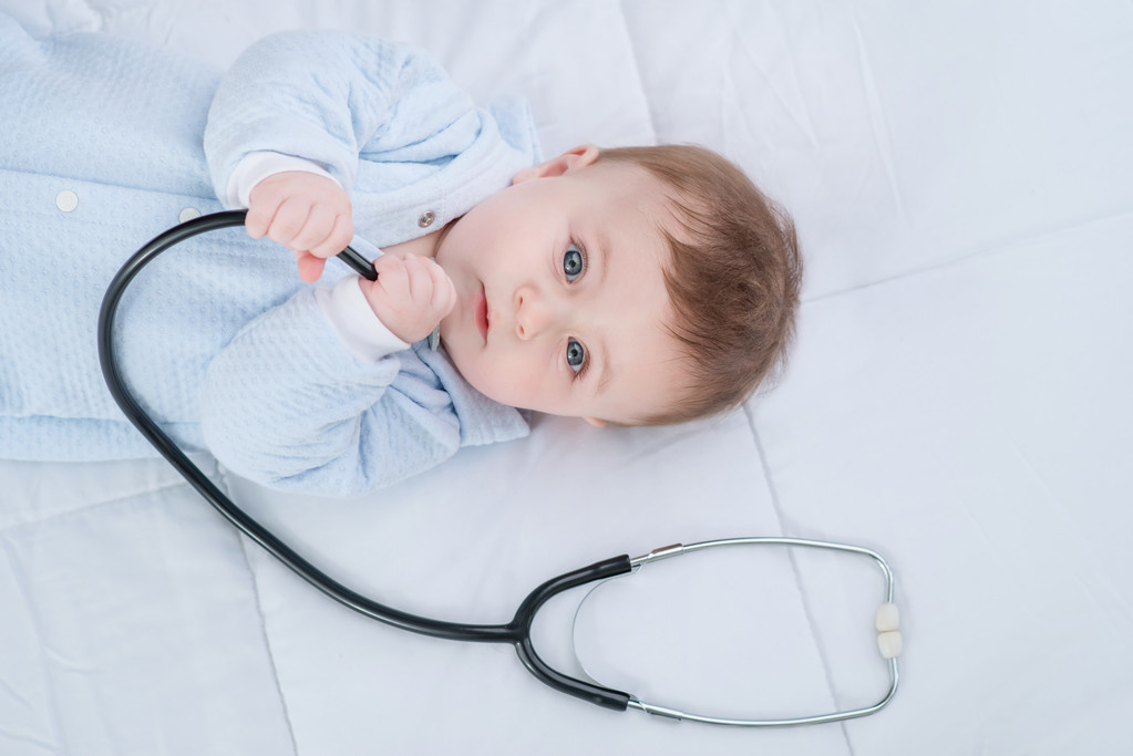 cute infant child lying with stethoscope on the couch