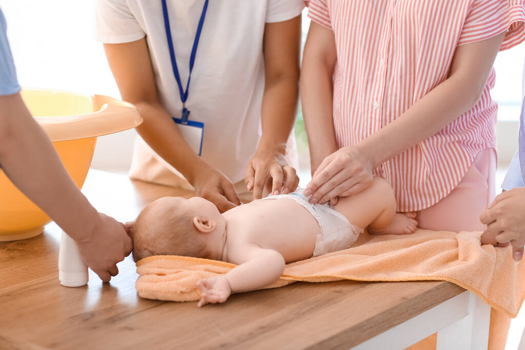young pregnant women learning how put diaper class closeup